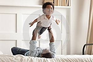 African American dad playing with toddler son in bedroom