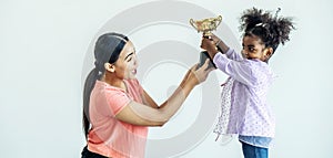 African american daughter express exciting after get reward as trophy from her mother, holding a trophy high up photo