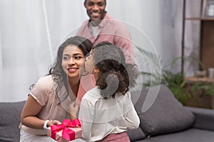 Daughter kissing mother and presenting gifts to her on mothers day