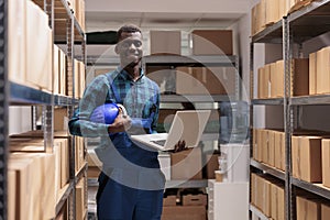 African american distribution center manager holding laptop in warehouse