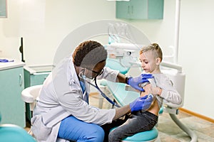 African American Doctor examining child by stethoscope. Happy child boy at the doctor`s consultation in hospital