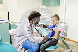 African American Doctor examining child by stethoscope. Happy child boy at the doctor`s consultation in hospital