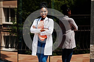 African american doctor female at lab coat with stethoscope posed outdoor against clinic