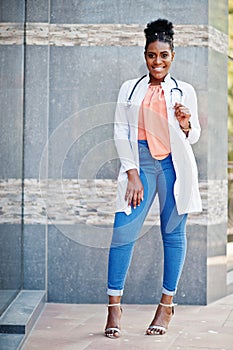 African american doctor female at lab coat with stethoscope posed outdoor against clinic