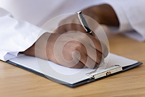 African American doctor filling patient form document close up