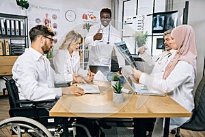 Team of five diverse medical workers having meeting at office
