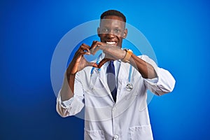 African american doctor man wearing stethoscope standing over isolated blue background smiling in love showing heart symbol and