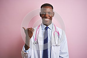 African american doctor man wearing stethoscope standing over isolated pink background smiling with happy face looking and