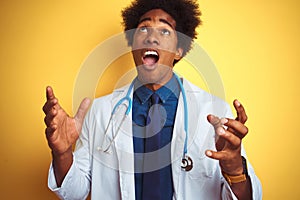 African american doctor man wearing stethoscope standing over isolated yellow background crazy and mad shouting and yelling with