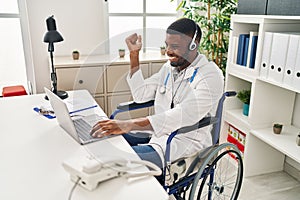 African american doctor man working on online appointment sitting on wheelchair screaming proud, celebrating victory and success