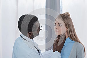 african american Doctor palpating female patient lymph