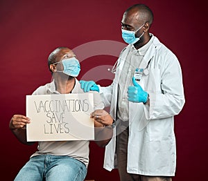African american doctor showing thumbs up sign and symbol after covid vaccine to black man wearing face mask. Patient