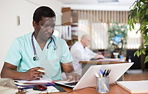 African american doctor therapist works at an computer, studying outpatient cards patients