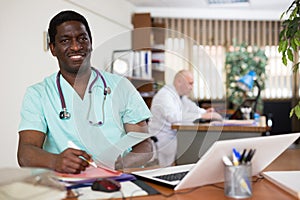 African american doctor therapist works at an computer, studying outpatient cards patients