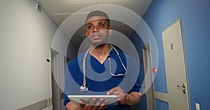 African American doctor uses a tablet in corridor of medical center