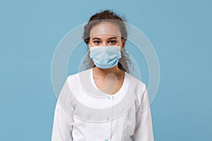 African american doctor woman isolated on blue background. Female doctor in white medical gown with sterile face mask