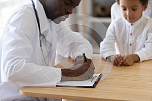 African American doctor write prescription to child patient