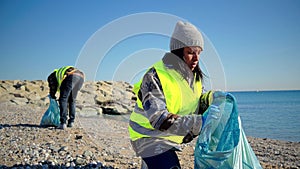 African american ecologist activist picking up waste of the beach. Volunteers cleaning plastic from the sand. People