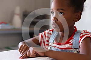 African american elementary schoolgirl looking away while studying on braille book in class