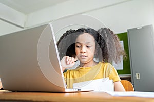 African American Elementary schoolgirl studying with laptop
