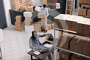 African american employee putting helmet order in cardboard box preparing packages for delivery