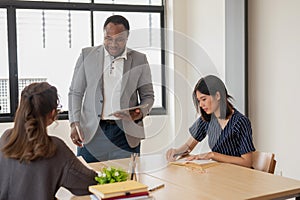 An African American English teacher or tutor is giving homework to Asian students