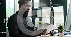African American Entrepreneur Managing Paperwork at a Computer in the Office