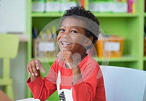 African American ethnicity kid smiling at library in kindergarten preschool classroom.happy emotion.education concept.