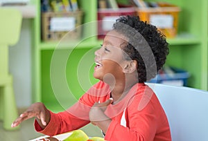 African American ethnicity kid smiling at library in kindergarten preschool classroom.happy emotion.education concept