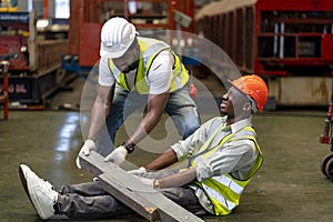 African American factory worker having accident while working in manufacturing site while his colleague is helping  for safety