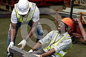 African American factory worker having an accident while working in manufacturing site while his colleague is helping for safety