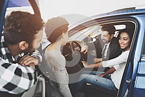 African american family at car dealership. Salesman is showing new car.