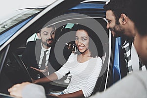 African american family at car dealership. Salesman is showing new car to mother.