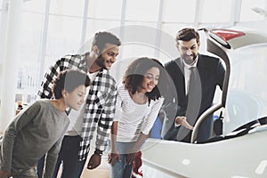 African american family at car dealership. Salesman is showing trunk of new car.