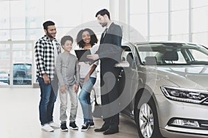 African american family at car dealership. Salesman is signing papers for new car.