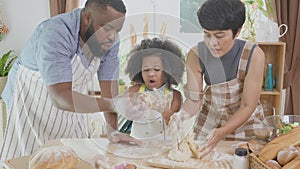 African American family with daughter thresh flour for cooking with father and mother together in the kitchen at home.