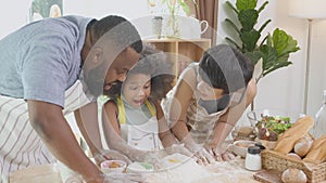 African American family with daughter thresh flour with excited for cooking with father and mother together.