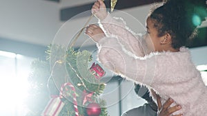 African American family decorated with ornament on Christmas tree at Christmas and New Year festival at home. Xmas celebration