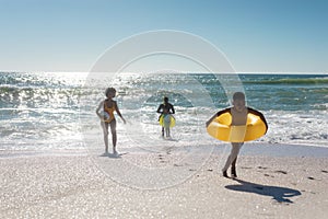 African american family enjoying summer holiday together at beach against clear sky on sunny day