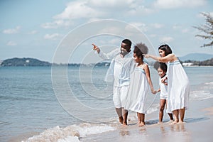 African American family. Happy family Mother, Father, Two daughters walking and playing together on the beach on holiday, having