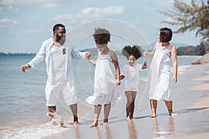 African American family. Happy family Mother, Father, Two daughters walking and playing together on the beach on holiday, having