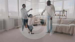 African american family having fun at home in living room afro little girl child toddler kid jumping high into air jump