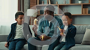 African American family at home single father man with two children boys dad talking with kids give bananas fruits