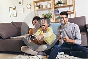 African American family at home sitting in sofa couch and playing console video games