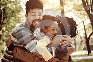 African American family hugging in park.