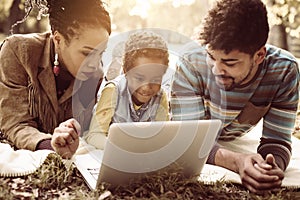 African American family in park and using laptop together. photo