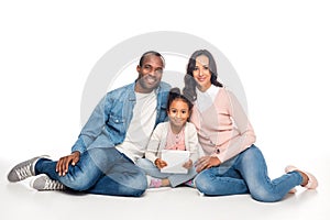 african american family with one child using digital tablet and smiling at camera