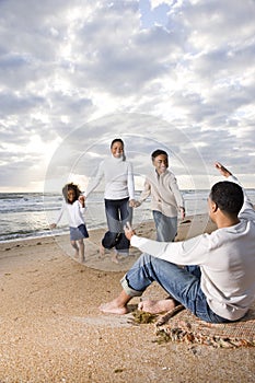 African-American family running to dad on beach