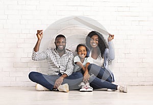 African American Family Sitting Under Roof Dreaming Of New Home.