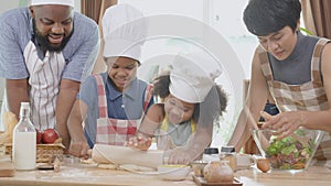 African American family with son and daughter rolling for thresh flour for cooking with father and mother together.